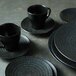 A black porcelain Luzerne Urban bowl on a stack of black plates.