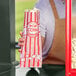 A person holding a red and white Carnival King popcorn bag.