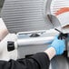 A person in blue gloves using the Avantco thickness adjustment knob on a meat slicer.