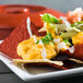 A plate of nachos with Gehl's Sharp Cheddar Cheese Sauce, lettuce, and vegetables.