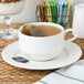 A close up of a Oneida warm white porcelain cup with a tea bag in it.