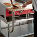 A chef uses a Regency wooden cutting board to cut pancakes on a counter.