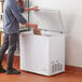 A man opening a Galaxy commercial chest freezer in a professional kitchen.