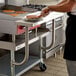 A man using a Regency stainless steel work surface in a commercial kitchen to cook pancakes.
