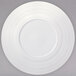 A white porcelain wide rim coupe plate with a circular pattern.