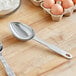 A silver stainless steel measuring scoop on a wooden table.