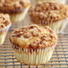 A close up of a muffin in a white fluted baking cup with brown crumbs on top.