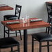 A Lancaster Table & Seating mahogany wood butcher block table top on a table with glasses and a napkin.