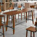 A large rectangular solid wood live edge table with a rustic walnut finish and industrial metal accents.