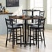 A Lancaster Table & Seating butcher block table with black chairs and plates on it.