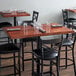 A Lancaster Table & Seating mahogany wood butcher block table with chairs and glasses on it.