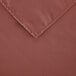 A close-up of a mauve rectangular cloth table cover with a corner hem.