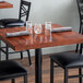 A Lancaster Table & Seating mahogany butcher block table with glasses and napkins on it.