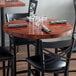 A Lancaster Table & Seating wood table with glasses and napkins on it.