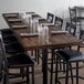 A wood table with glasses and chairs set on it in a restaurant.