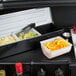 A white container with a variety of fruit and vegetables in a metal tray.