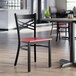 A black metal cross back chair with a mahogany wood seat.