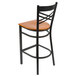 A Lancaster Table & Seating black cross back bar stool with a cherry wood seat.