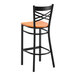 A black metal bar stool with a cross back design and a cherry wood seat.