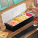 A four-compartment condiment bar containing sliced fruits and cherries, used for drink garnishes.