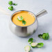 A silver Bon Chef stainless steel fondue pot of soup with broccoli and greens.