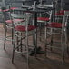 A Lancaster Table & Seating cross back bar stool with a mahogany wood seat on a table in a restaurant.