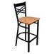 A black metal bar stool with a cross back design and a natural wood seat.