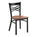 A black metal chair with a cross back design and an antique walnut wood seat.