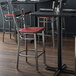 A Lancaster Table & Seating cross back bar stool with a mahogany wood seat on a table in a restaurant dining area.