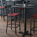 A black finish cross back bar stool with a mahogany wood seat.