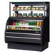 A black Turbo Air refrigerated display case with food on shelves.