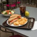 A Carlisle chocolate plastic fast food tray with a sandwich and chips on it.