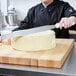 A woman using a Tablecraft baking spatula to cut a cake.