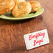 An American Metalcraft rectangular ceramic card sign on a plate of everything bagels on a table.
