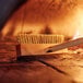 A Chef Master pizza oven brush with a wooden head sitting on a wood surface.