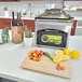 An ARY VacMaster VP215 chamber vacuum packaging machine on a kitchen counter with vegetables.