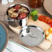 A stainless steel American Metalcraft mini pot with a lid on a cutting board filled with potatoes and vegetables.