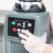 A person using a Waring stainless steel food blender in a professional kitchen.