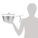 A woman holding a Vollrath Arkadia aluminum sauce pan over a metal surface.