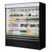 A black Turbo Air vertical display case filled with drinks and beverages on shelves.