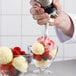 A person using an iSi Tulip Decorator Tip to pipe yellow and pink frosting on a bowl of ice cream.