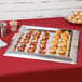 A Vollrath stainless steel square serving tray with appetizers on a table.