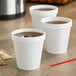 Three Dart white foam cups filled with brown liquid on a counter.