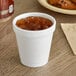 A Dart white foam cup filled with brown liquid on a counter.