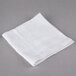 A 12-pack of white Oxford wash cloths on a gray surface.