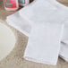 A stack of white Oxford open end wash cloths on a white counter.
