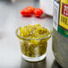 A small glass cup of B&G sweet relish on a counter next to a bottle of salsa.