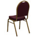 A Flash Furniture banquet chair with a gold metal frame and burgundy pattern fabric.
