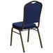 A navy blue banquet chair with blue and gold dotted fabric on the back.