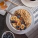 A bowl of oatmeal with blueberries, bananas, and honey on a table.